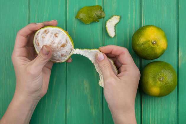 食物俯视图：女性在绿色墙上剥橘子皮柑橘橘子视野