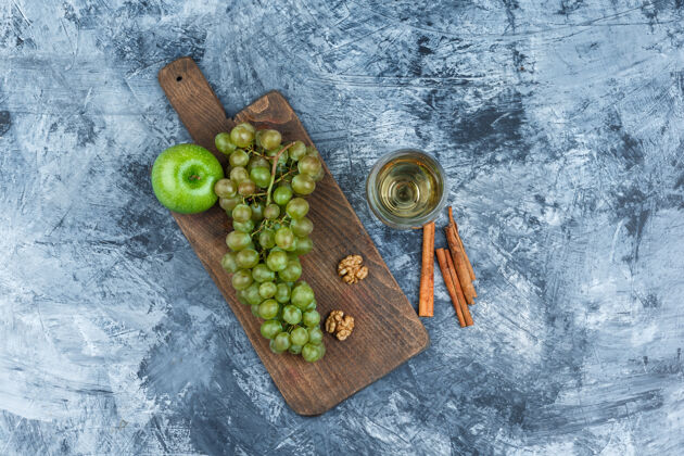 威士忌白葡萄 核桃 苹果放在砧板上 配上一杯威士忌 肉桂色的顶视图放在深蓝色大理石背景上酿酒厂饮食玻璃