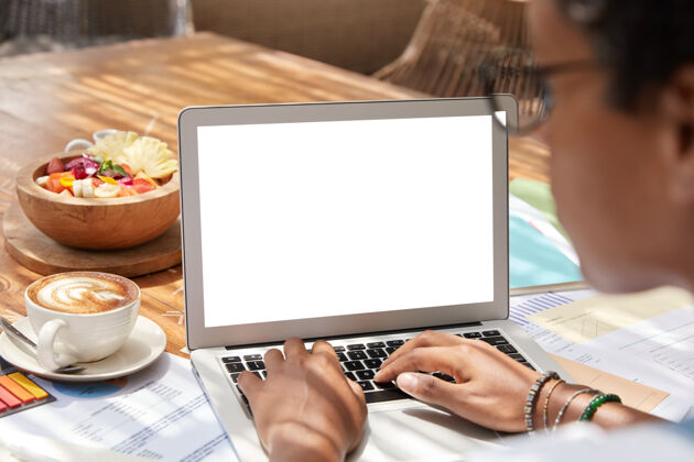显示女商人在上网本上工作的后视图无线笔记本电脑咖啡