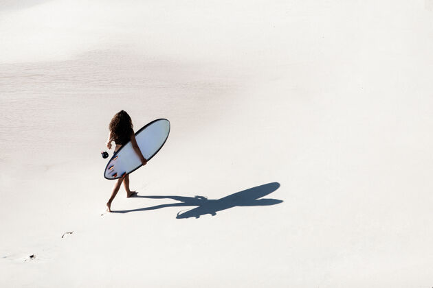 海洋美丽的女孩拿着冲浪板走在荒野的海滩上从山顶看风景很美海洋漂亮年轻