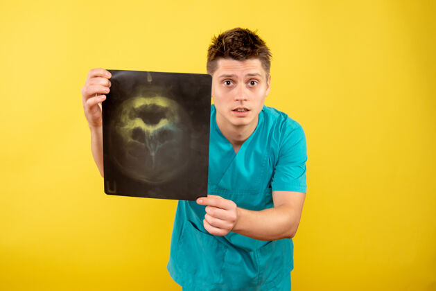 医学正面图身穿医疗服的年轻男医生拿着黄色背景的x光片持有背景健康