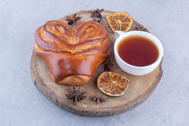 小吃八角干柠檬片 一杯茶和一个甜面包放在大理石表面的木板上柠檬糕点烘焙食品