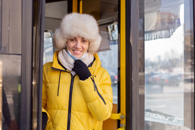 道路阳光明媚的肖像画一个穿着暖和衣服的年轻女子开心地微笑着下车 摘下她的防护面罩围巾旅行街道