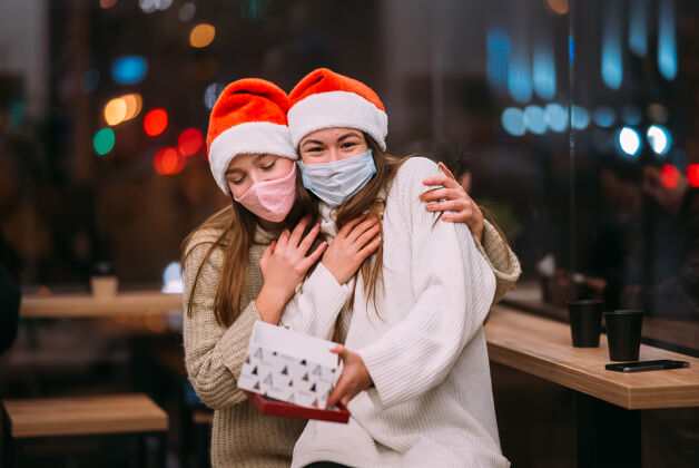 冬天那个女孩在咖啡馆给她的女朋友送礼物圣诞帽给予保护面具