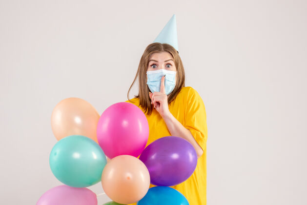 健康年轻的女性手持彩色气球 戴着白色的无菌口罩生日大流行举行
