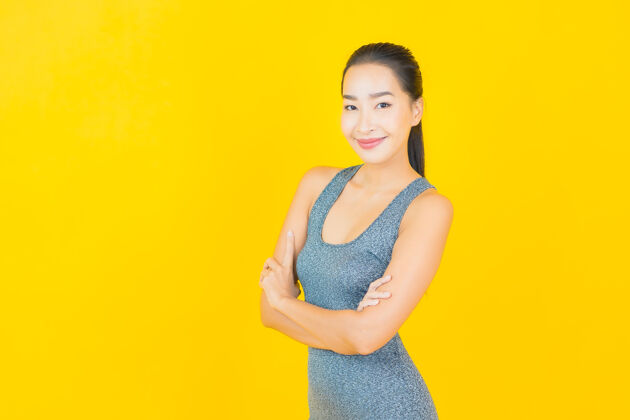 人在黄色的墙上 描绘一位穿着运动服准备锻炼的美丽亚洲年轻女子运动皮肤护理体重