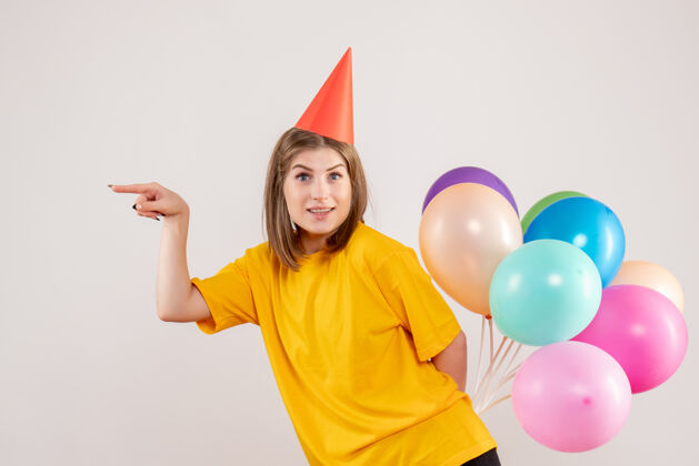 人年轻的女性把彩色的气球藏在白色的背上气球情感生日