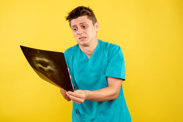 病毒正面图黄色背景上穿着医疗服拿着x光片的年轻男医生医学健康年轻的男医生