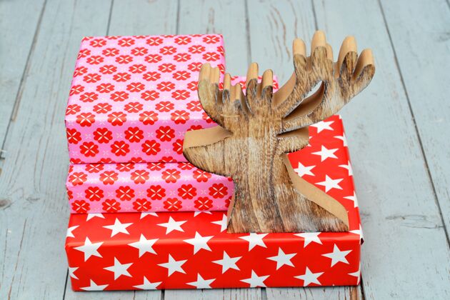 堆叠特写镜头的红色礼品盒堆叠在一起 一个木制驯鹿的数字装饰品季节包装