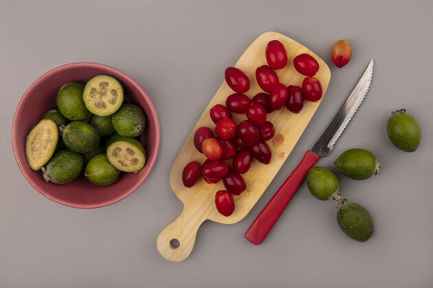 刀顶视图绿色新鲜的feijoas在一个碗上 在一个木制的厨房板上放着一把小刀 在灰色的墙上放着一个科尼尔樱桃新鲜厨房视野