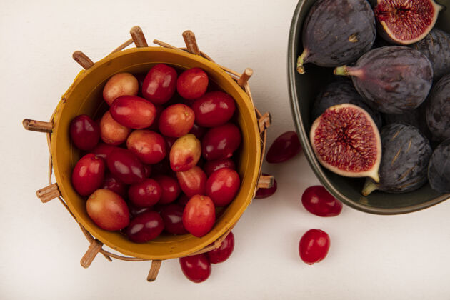 新鲜一个碗上新鲜成熟的黑色无花果的俯视图 白色墙壁上的桶上放着一个山茱萸樱桃有机食品碗