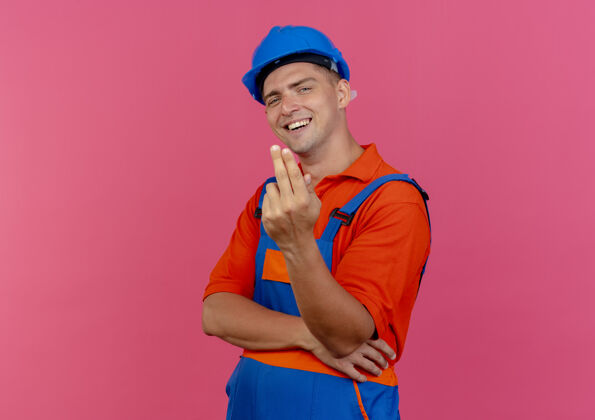 安全帽高兴的年轻男性建筑工人穿着制服和安全帽显示两个粉红色男制服两个
