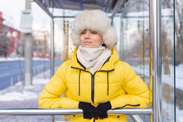 漂亮在寒冷的日子里 一个穿着冬衣的女人在公共汽车站等公共汽车车站围巾公共