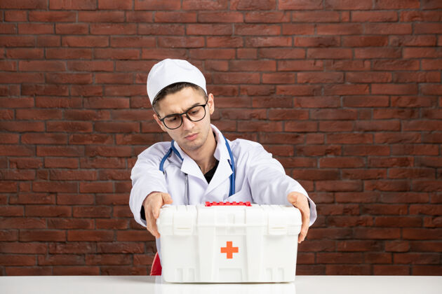 护士前视图身穿白色医疗服的年轻医生带着急救箱工具箱视图前面