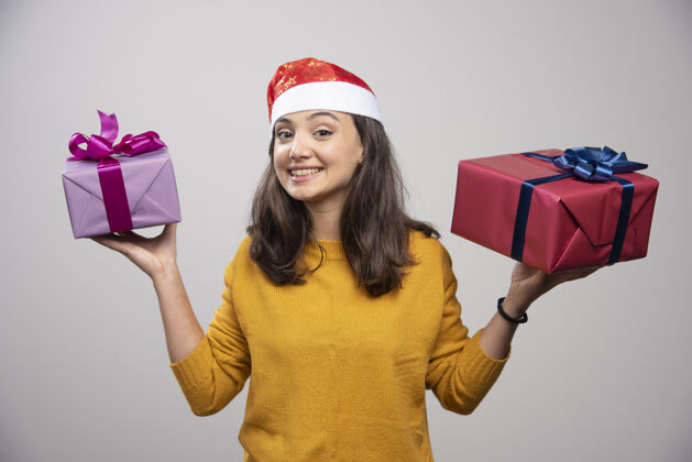 模型戴着圣诞老人红帽子的微笑的女人 带着圣诞礼物女人礼品盒人