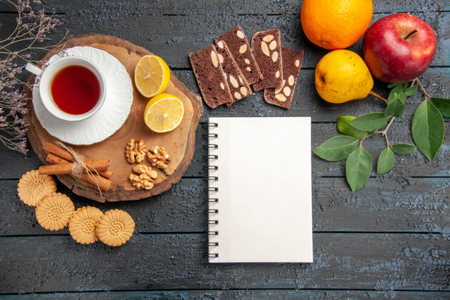 柑橘在一张深色的桌子上俯瞰一杯水果和糖果的茶健康笔记本甜点