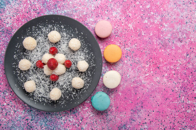 生的俯瞰美味的椰子糖甜球与法国马卡龙在粉红色的表面饼干鸡蛋可口