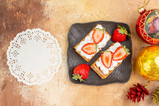 盘子顶视图美味奶油蛋糕与水果和节日树玩具在一个轻背景袋子饼干美食