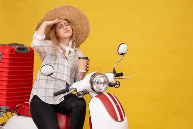 可爱体贴的年轻女子戴着帽子坐在摩托车上收拾行李 出示车票坐人肖像