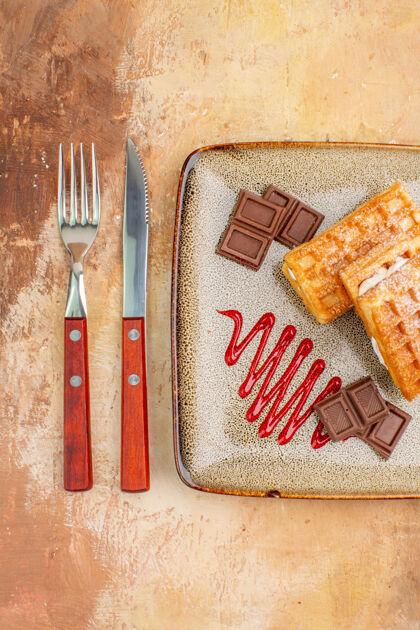 刀俯瞰美味的华夫饼与巧克力条在棕色的背景甜点饼干背景