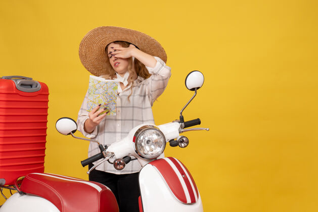 抱着俯视图：疲惫的年轻女子戴着帽子 坐在摩托车上拿着地图 收拾行李摩托车车辆摩托车