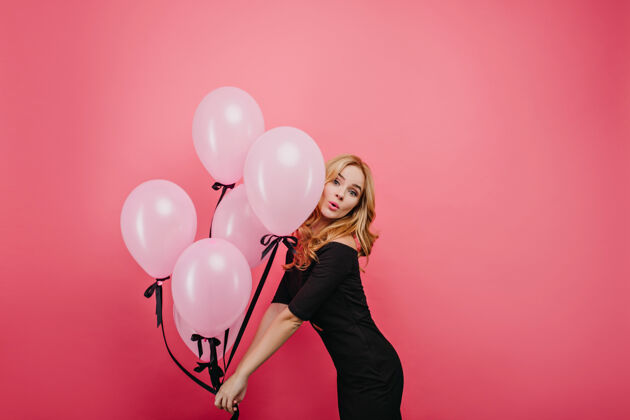 寒冷美丽的白人女模特在活动中翩翩起舞快乐的高加索卷发女人 手拿一束粉红色的气球快乐室内成人