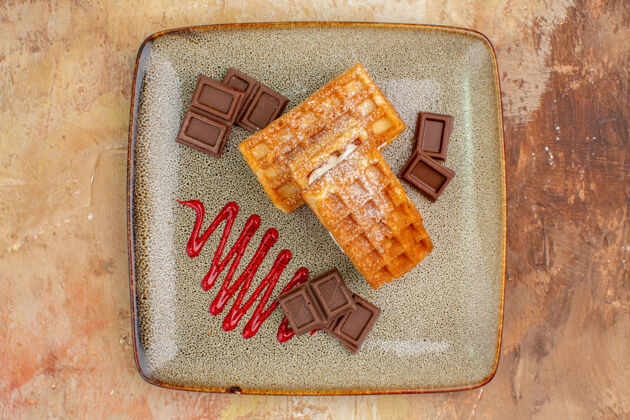 甜点俯瞰美味的华夫饼与巧克力条棕色背景粗麻布包纸