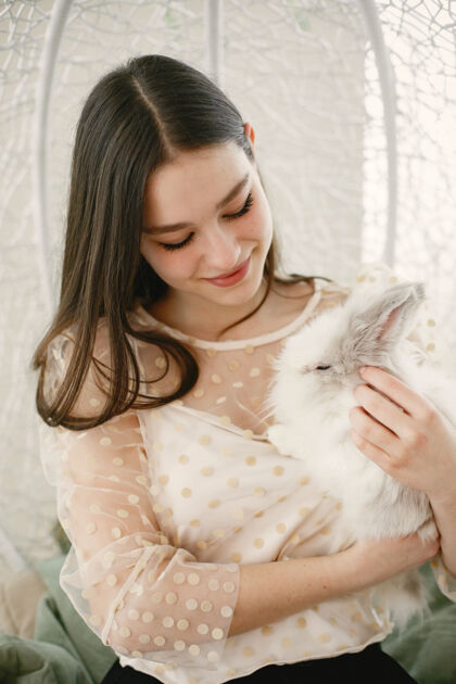 年轻长头发的女孩女孩怀里抱着白兔动物室内早晨