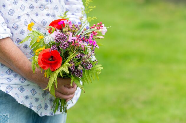 开花有选择的焦点拍摄的一个人持有一束不同的花在户外白天花绿色女人