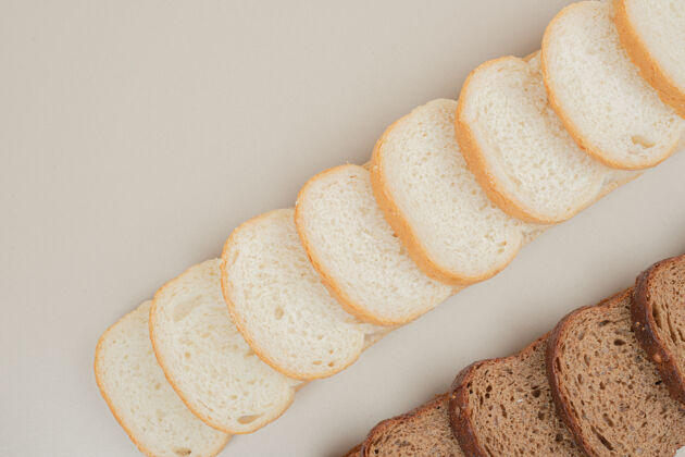 谷类把新鲜的白面包和棕色面包切片放在白色的表面上美食切烘焙