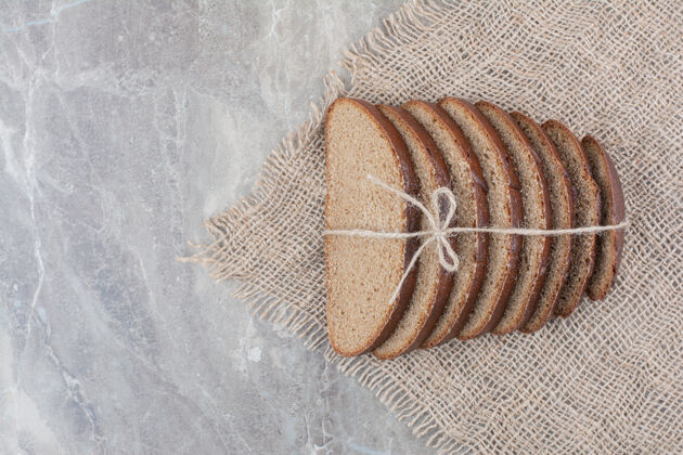 自然用绳子把棕色面包片放在大理石表面切面包谷物