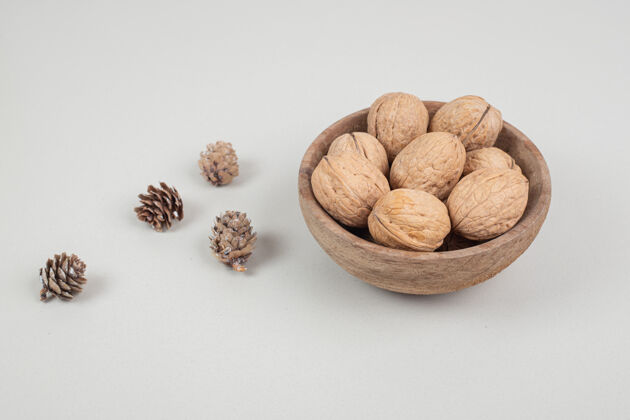 天然一碗核桃和松果放在米色的表面木材坚果核桃