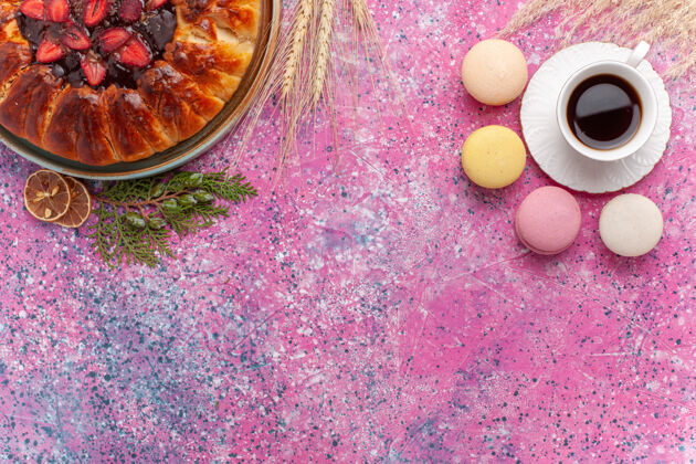 杏仁饼顶视图美味的草莓派与一杯茶和麦卡龙粉红杯子蛋糕咖啡