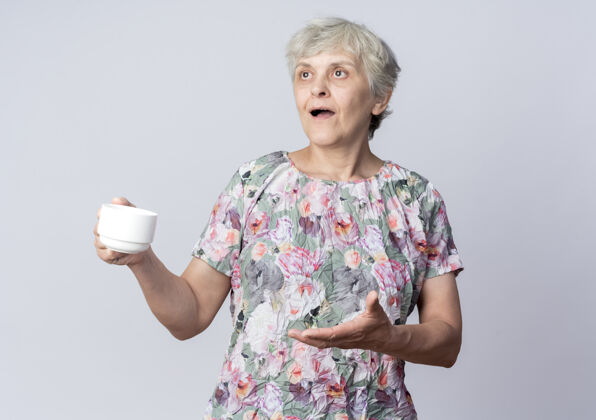 杯子惊讶的老妇人拿着杯子 望着隔离在白墙上的一边壁板拿着老人