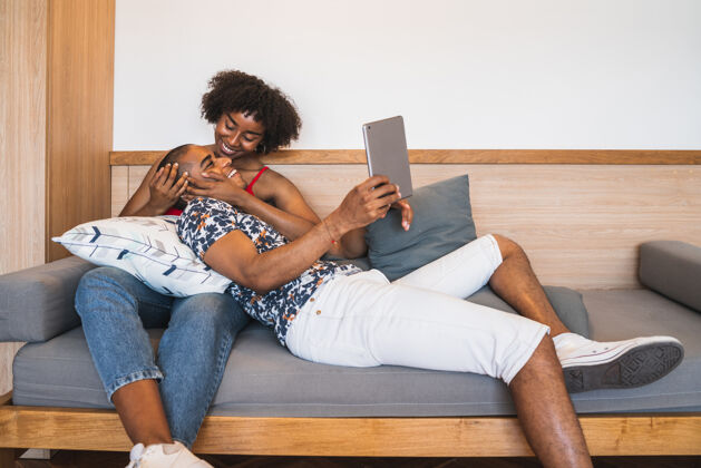 触摸板一对年轻的拉丁夫妇在家里用数字平板电脑自拍的照片沙发放松电脑