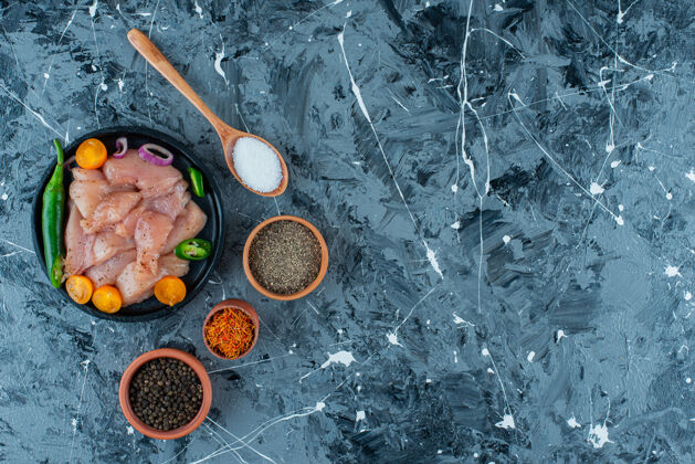 香料把腌制好的肉和蔬菜放在盘子里 放在碗和勺子里的香料旁边 蓝色背景蛋白质汤匙胡萝卜