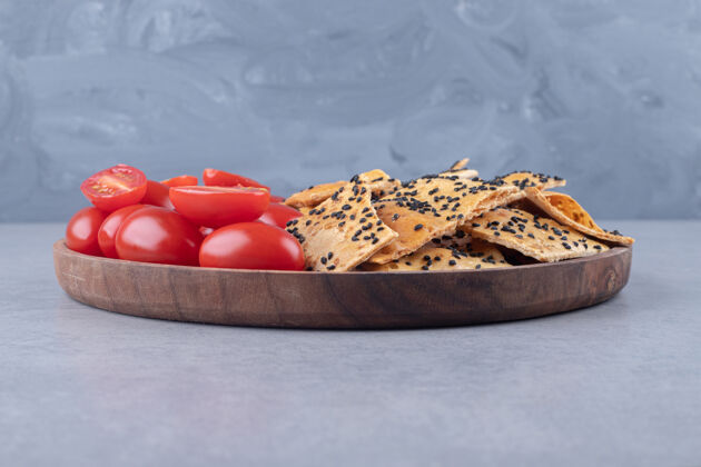 面包芝麻面包和番茄片堆在大理石桌上的木制托盘上外套芝麻烘焙食品