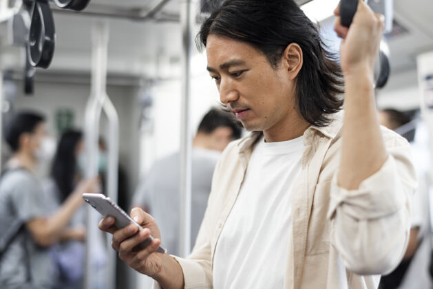 街头一个日本男人在火车上玩手机独自一人城市个人
