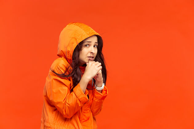 年轻在摄影棚摆造型的年轻女孩 穿着红色的秋夹克人类的负面情绪寒冷天气的概念女性时尚的概念外套聪明季节