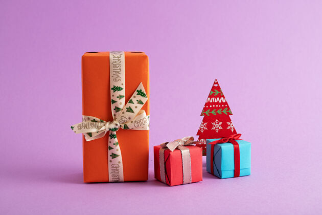 礼物特写彩色礼品盒和纸圣诞树在紫色的背景水平圣诞节庆祝