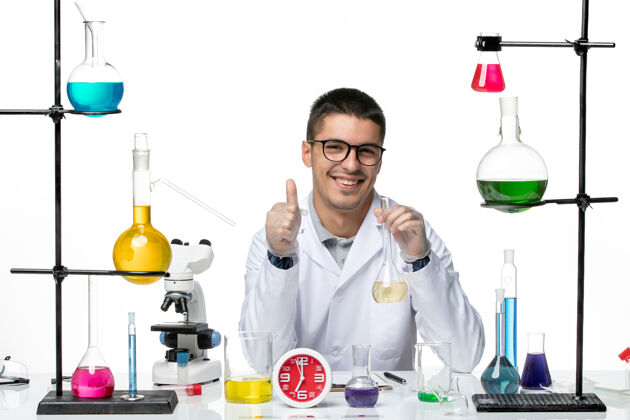 视图正面图身穿白色医疗服的男性化学家拿着装有溶液的烧瓶 微笑着面对白色背景病毒科学实验室的病毒-大流行专业医学实验室