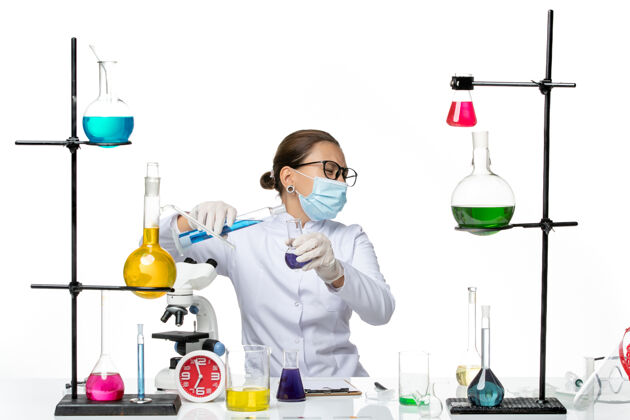 解决方案前视图：穿着医疗服的女化学家 带着面罩 白色背景上混合着溶液病毒化学实验室的covidsplash科学诊所实验室