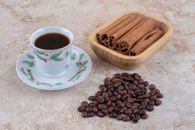 一杯咖啡旁边是一捆捆的肉桂条和咖啡豆豆子咖啡芳香