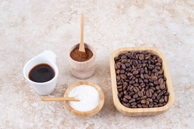 研磨把咖啡杯 糖 磨碎的咖啡粉和一堆咖啡豆放在一个木盘里糖勺子粉末