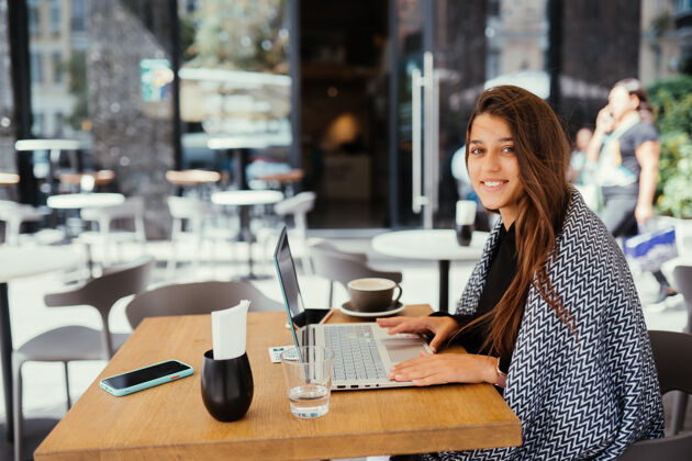 区域一位年轻漂亮的女士在便携式笔记本电脑上工作 迷人的女学生坐在咖啡馆里用上网本教育网络便携