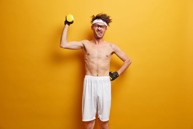 身体身体护理和锻炼理念不高兴的欧洲男人举起运动器材 用力量举起杜姆贝尔 穿着短裤和手套 努力实现目标 引领积极的生活方式举重室内健美