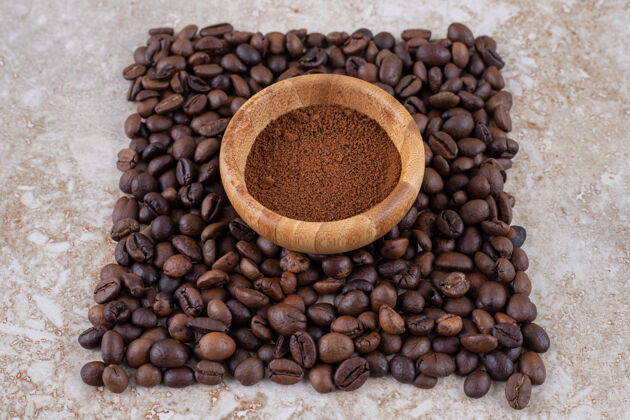 堆装着咖啡粉的小碗里围着一小堆咖啡豆芳香咖啡粉