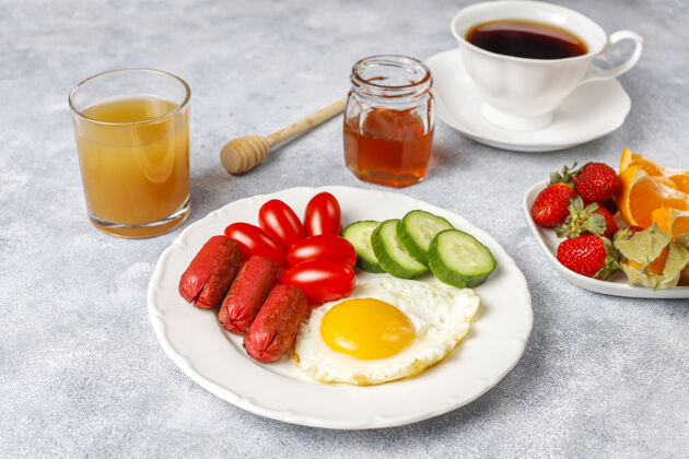 盘子早餐盘子里有鸡尾酒香肠 煎蛋 樱桃番茄 糖果 水果和一杯桃子汁咖啡视图蔬菜