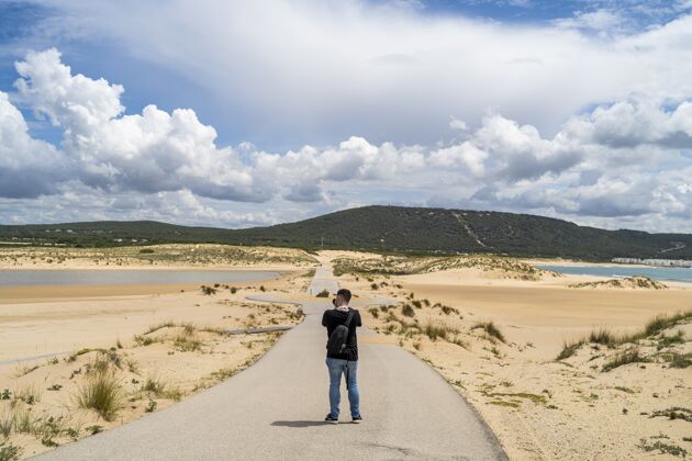 男人西班牙安达卢西亚 一位男摄影师白天在多云的天空下走过海滩风景安达卢西亚绿色