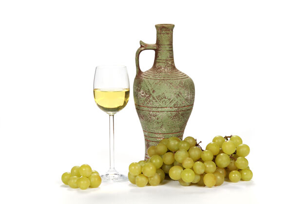 收获一杯白葡萄酒旁边是一个酒壶 上面放着绿葡萄 白色的树叶光线葡萄